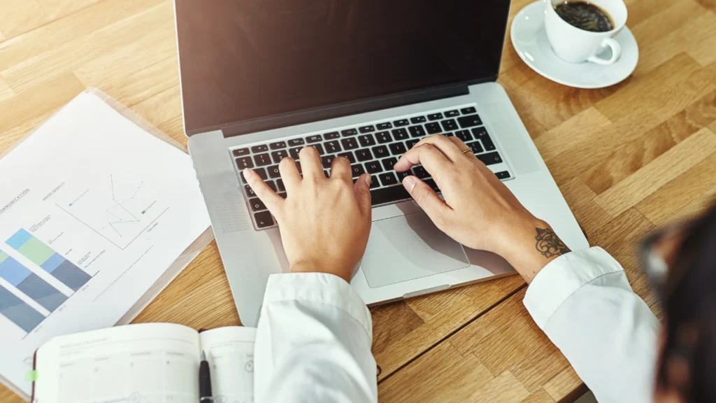 Un ordinateur avec une personne qui écrit sur son clavier en cherchant la performance, la productivité, l'efficacité et la fortune personnelle