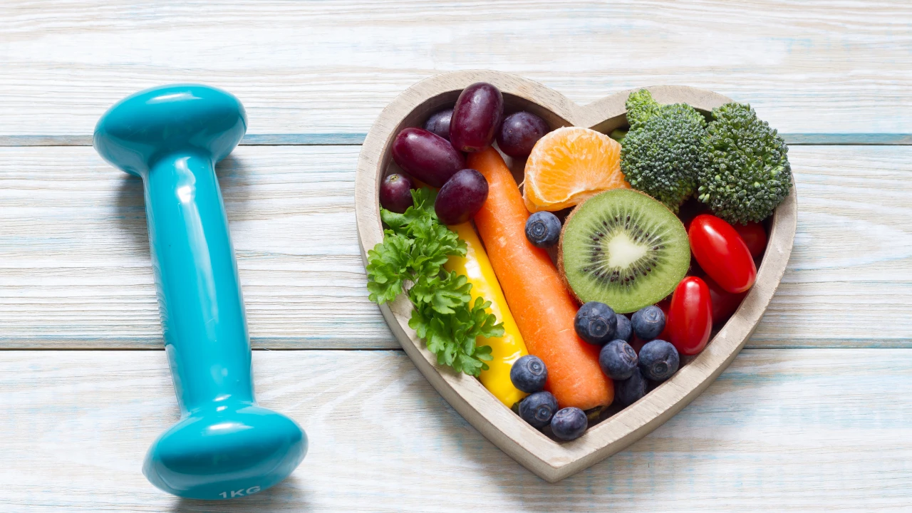 Un haltère avec de la nourriture saine à côté dans un plateau en forme de cœur