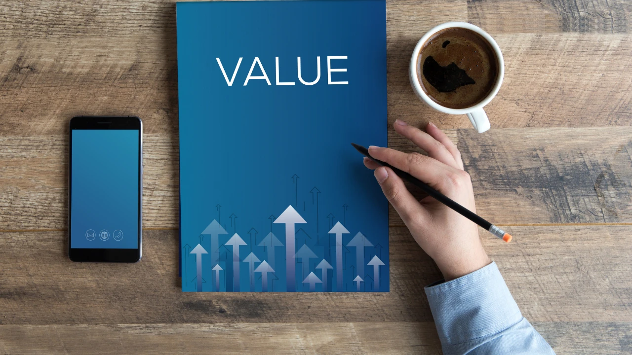Bureau sur lequel il y a un cahier écrit "VALUE" (valeurs, en français), une téléphone et une tasse de café. 