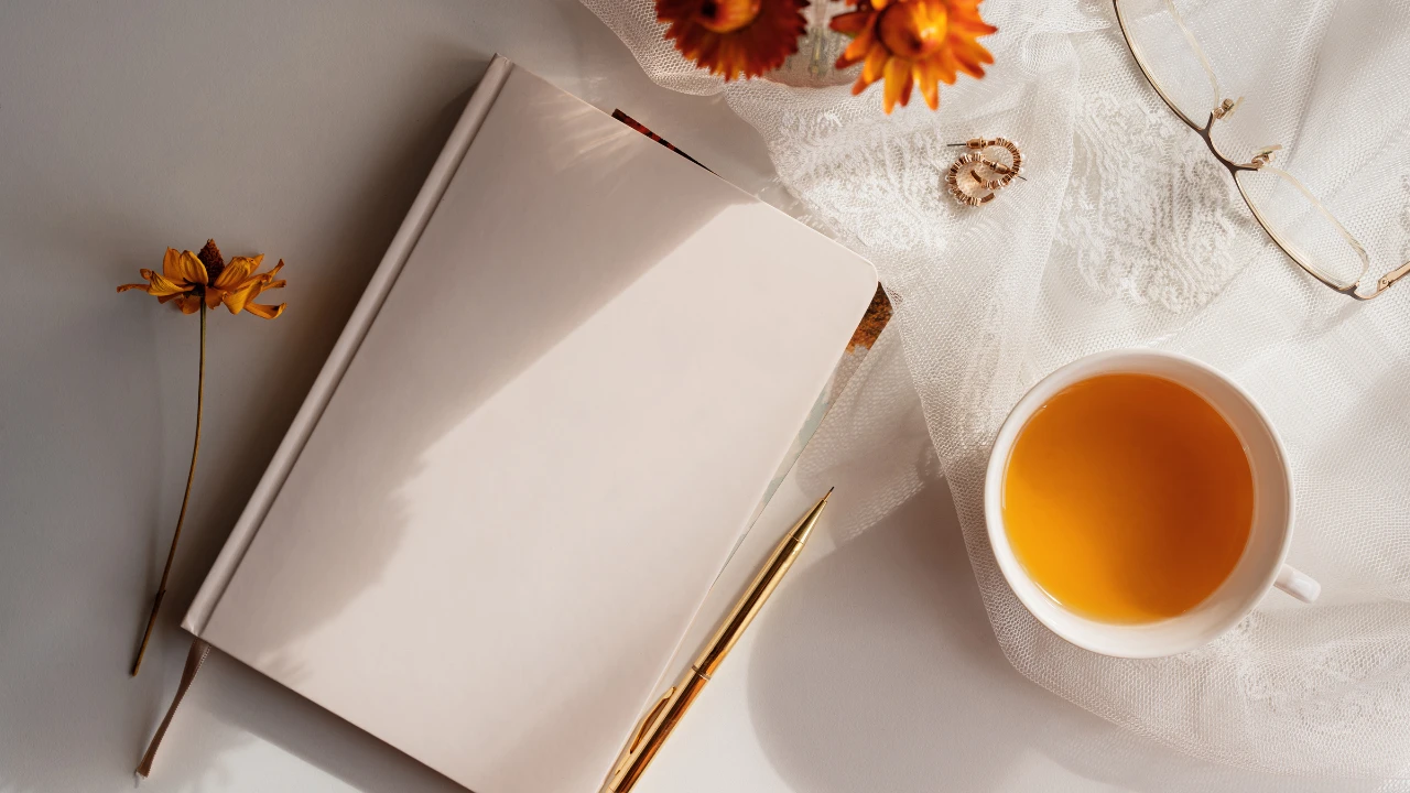 Un carnet avec un stylo à côté et une tasse avec une boisson chaude. Prêt pour du journaling ?