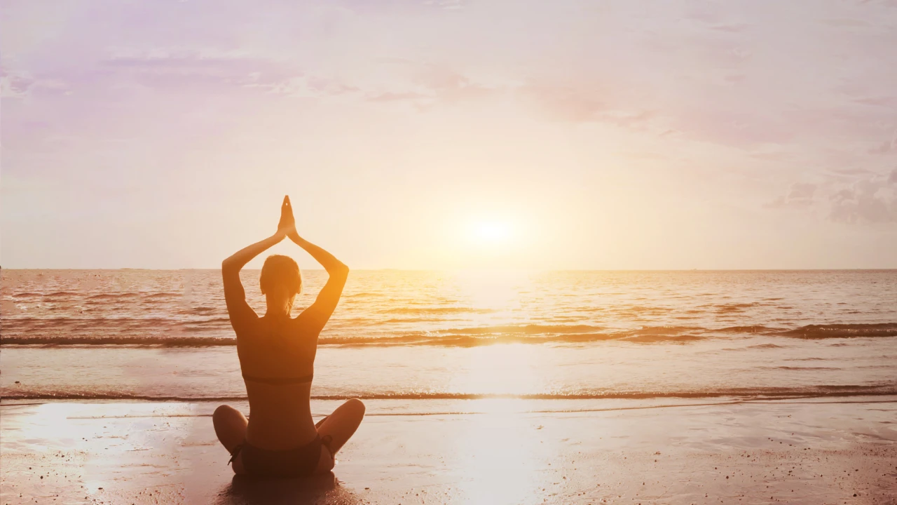 Femme qui médite et est en pleine conscience sur la plage au coucher de soleil