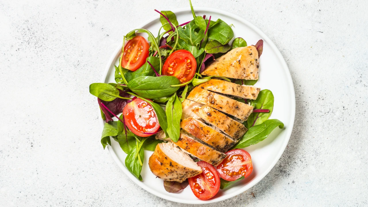 Un plat dans une assiette avec un morceau de viande blanche à droite et des légumes à gauche