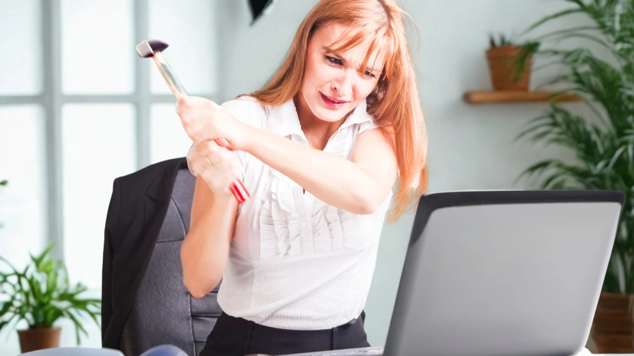 Une femme en colère qui va briser son ordinateur avec un marteau pour se déconnecter des réseaux sociaux