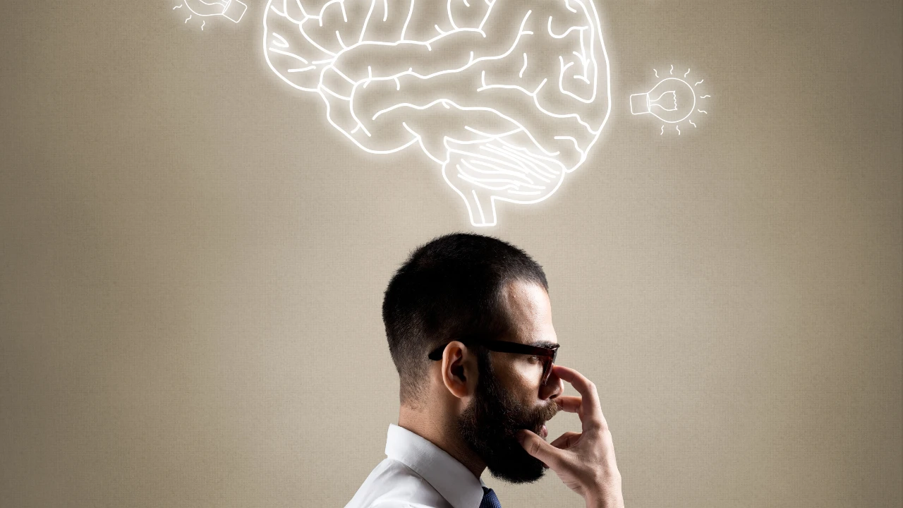 Un homme barbu qui réfléchit pour maîtriser ses perceptions, avec un cerveau juste au dessus de lui